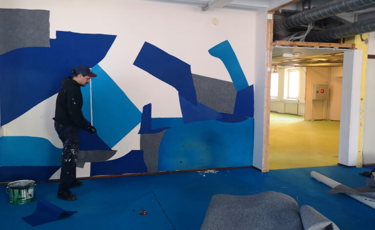Pinni47:n tiloissa taiteilija JP Köykkä tekee seinämaalausta.