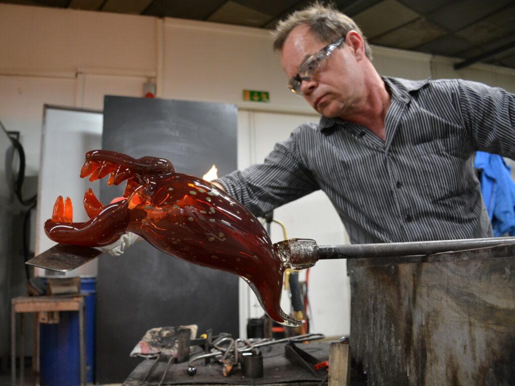 Lasinpuhaltaja Johannes Rantasalo työssään muotoilemassa lasista hirviöhahmoa.