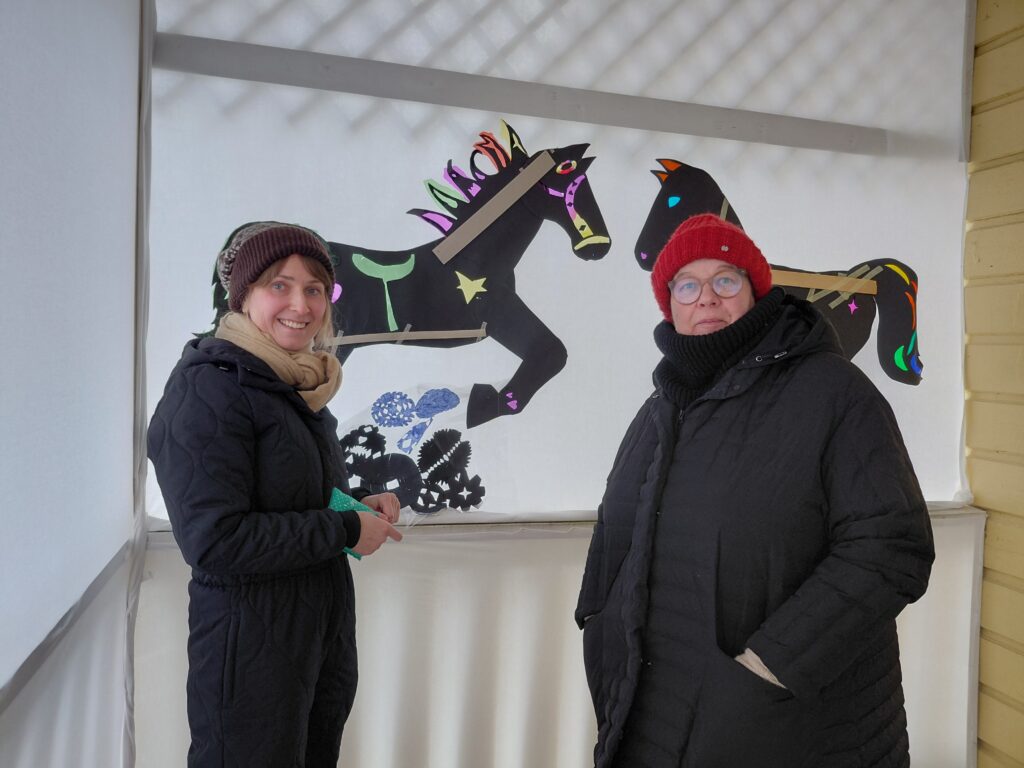Kuvassa Tuuli ja Minna ovat asettelemassa lasten taideteosta ukona.