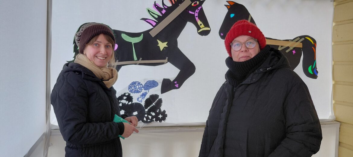 Kuvassa Tuuli ja Minna ovat asettelemassa lasten taideteosta ukona.